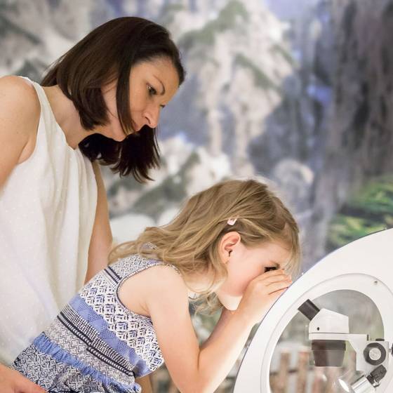 Kind schaut durchs Mikroskop, Mutter steht dahinter. Kind schaut durchs Mikroskop, Mutter steht dahinter.