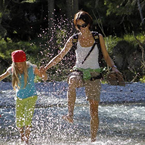 Mutter und Tochter hüpfen in einem Bach, das Wasser spritzt (Foto: FamilienUrlaub Steiermark/Photo Austria)