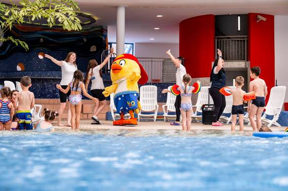 Kinderbetreuung in der H2O Hotel-Therme Kinderbetreuerin spielt mit Kindern am Beckenrand in der H2O Therme