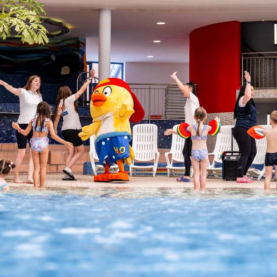 Kinderbetreuerin spielt mit Kindern am Beckenrand in der H2O Therme
