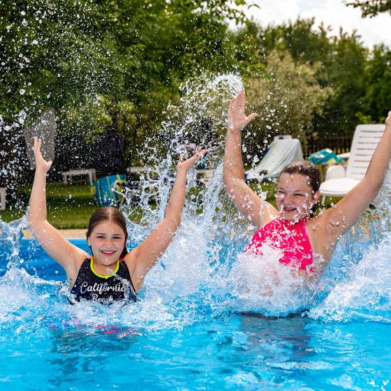 2 Mädchen im Pool, beide lachen und strecken die Arme nach oben (Familienurlaub Steiermark, Foto: Harry Schiffer)