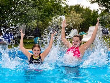 2 Mädchen im Pool, beide lachen und strecken die Arme nach oben (Familienurlaub Steiermark, Foto: Harry Schiffer)