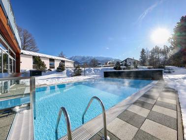 Dampfender Außenpool in verschneiter Landschaft