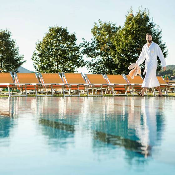 Mann im Bademantel geht den Pool entlang. Mann im Bademantel geht den Pool entlang.