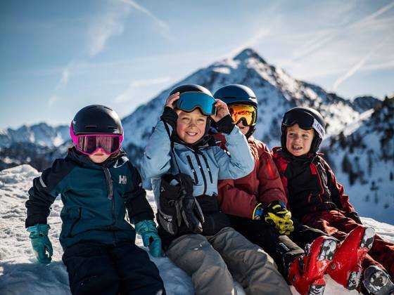 Vier Kinder in Skiausrüstung im Schnee sitzend (Foto: Jakob Ertl).