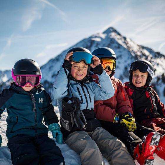 Vier Kinder in Skiausrüstung im Schnee sitzend (Foto: Jakob Ertl).